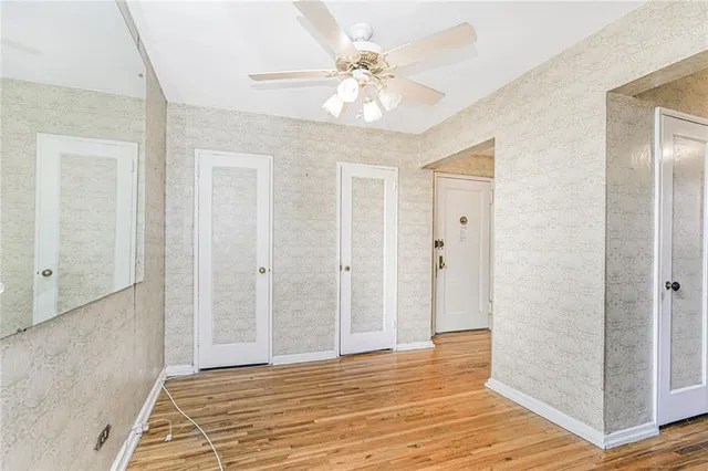 a view of an empty room with window and wooden floor