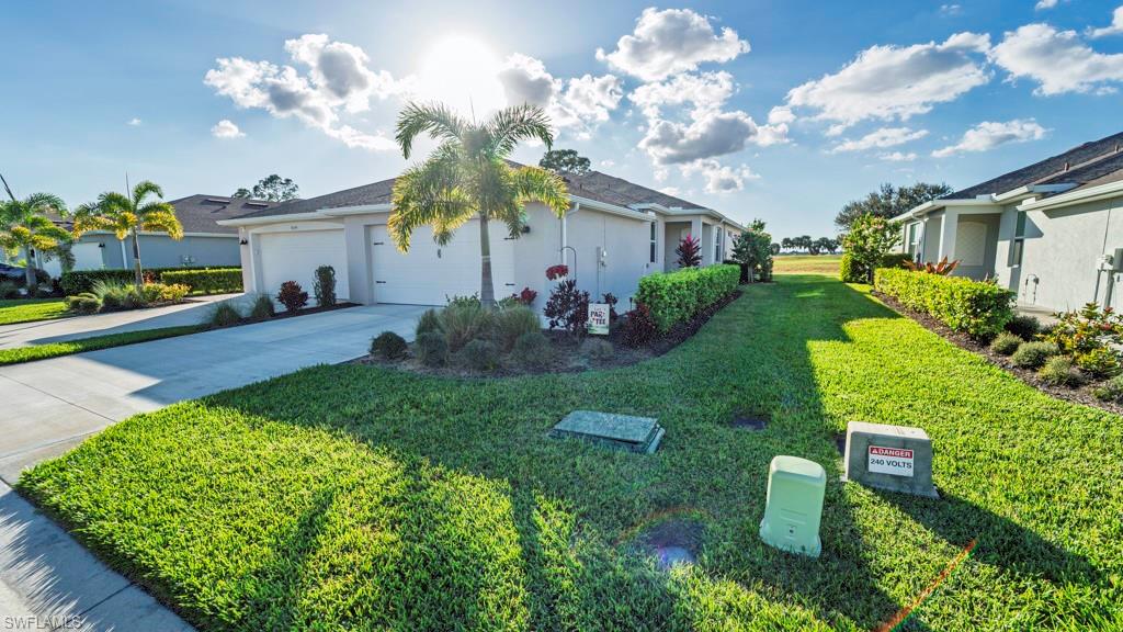 9092 Leatherwood Loop Lehigh Acres, FL 33936 - Photo 37 of 41 View of home's exterior featuring stucco siding, driveway, a garage, and a lawn