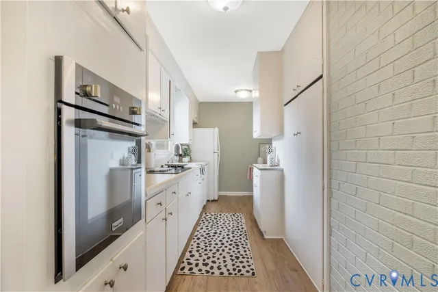 a kitchen with stainless steel appliances a refrigerator a sink and white cabinets