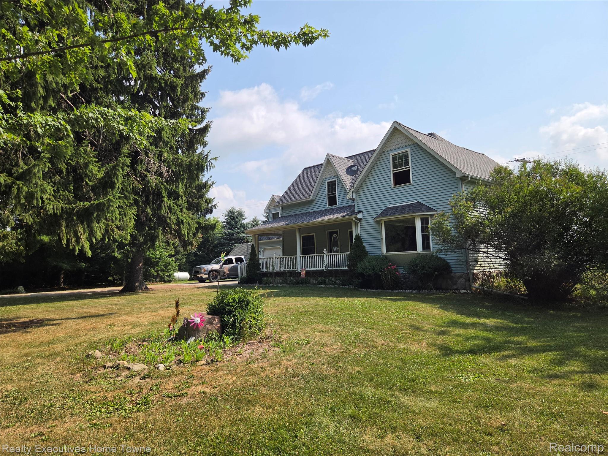 2715 Cash Road Applegate, MI 48401 - Photo 1 of 59 Traditional-style residence featuring light blue siding, a covered front porch with white railings, and a prominent bay window