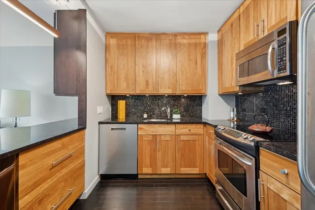 a kitchen with stainless steel appliances granite countertop wooden cabinets stove top oven and sink