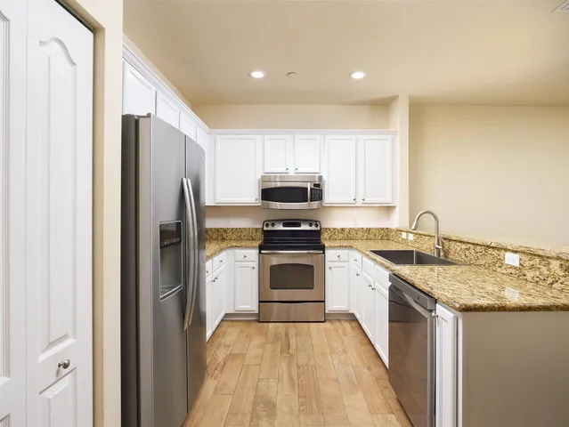 a kitchen with granite countertop a sink stove and refrigerator