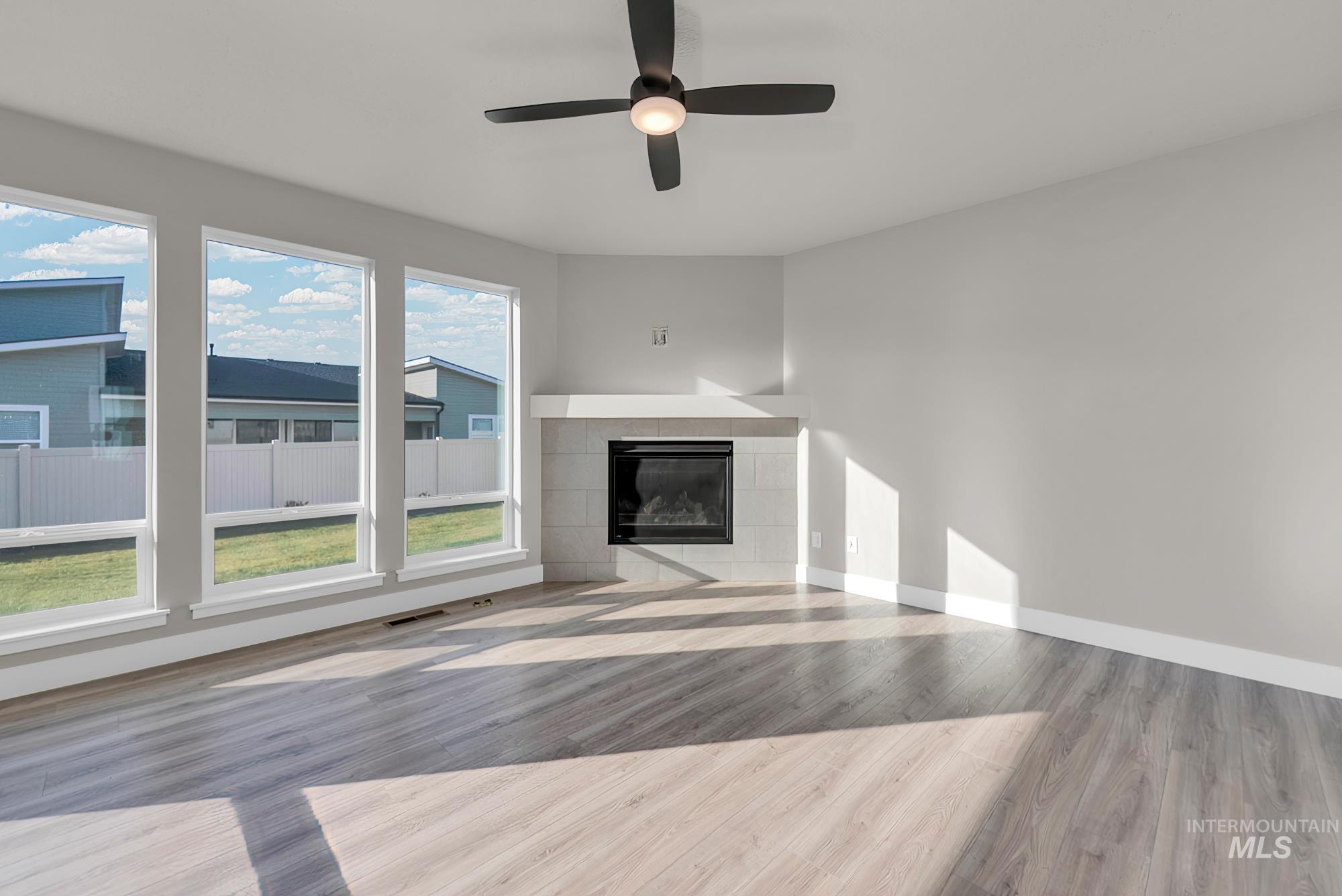 2807 West Jutland Street Meridian, ID 83642 - Photo 3 of 25 Unfurnished living room with a tiled fireplace, light wood-type flooring, and ceiling fan