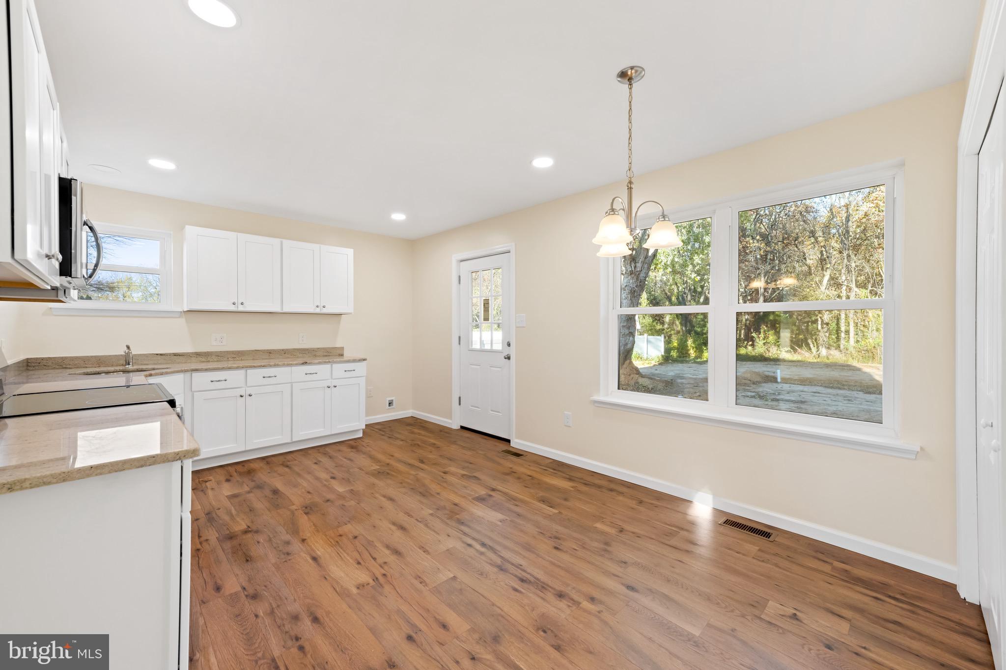 1488 North Tuckahoe Road Williamstown, NJ 08094 - Photo 6 of 27 a kitchen with stainless steel appliances granite countertop a refrigerator a sink dishwasher and white cabinets with wooden floor