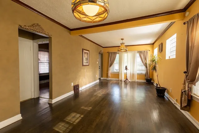 a view of an empty room with wooden floor and windows