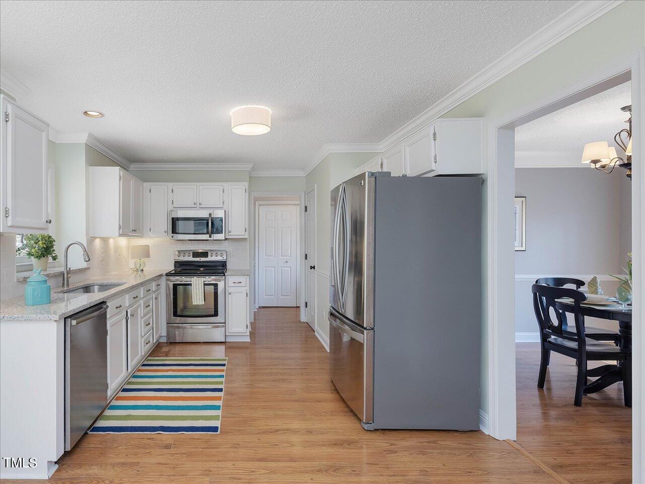 4818 Glendarion Drive Durham, NC 27713 - Photo 24 of 44 a kitchen with stainless steel appliances a refrigerator and wooden cabinets