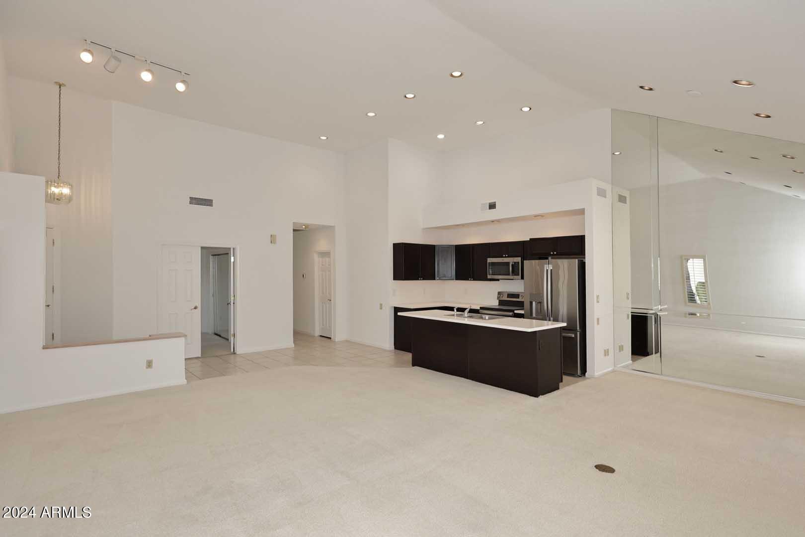 7272 East Gainey Ranch Road, Unit 55 Scottsdale, AZ 85258 - Photo 14 of 35 a large white kitchen with stainless steel appliances kitchen island a sink a stove and a refrigerator