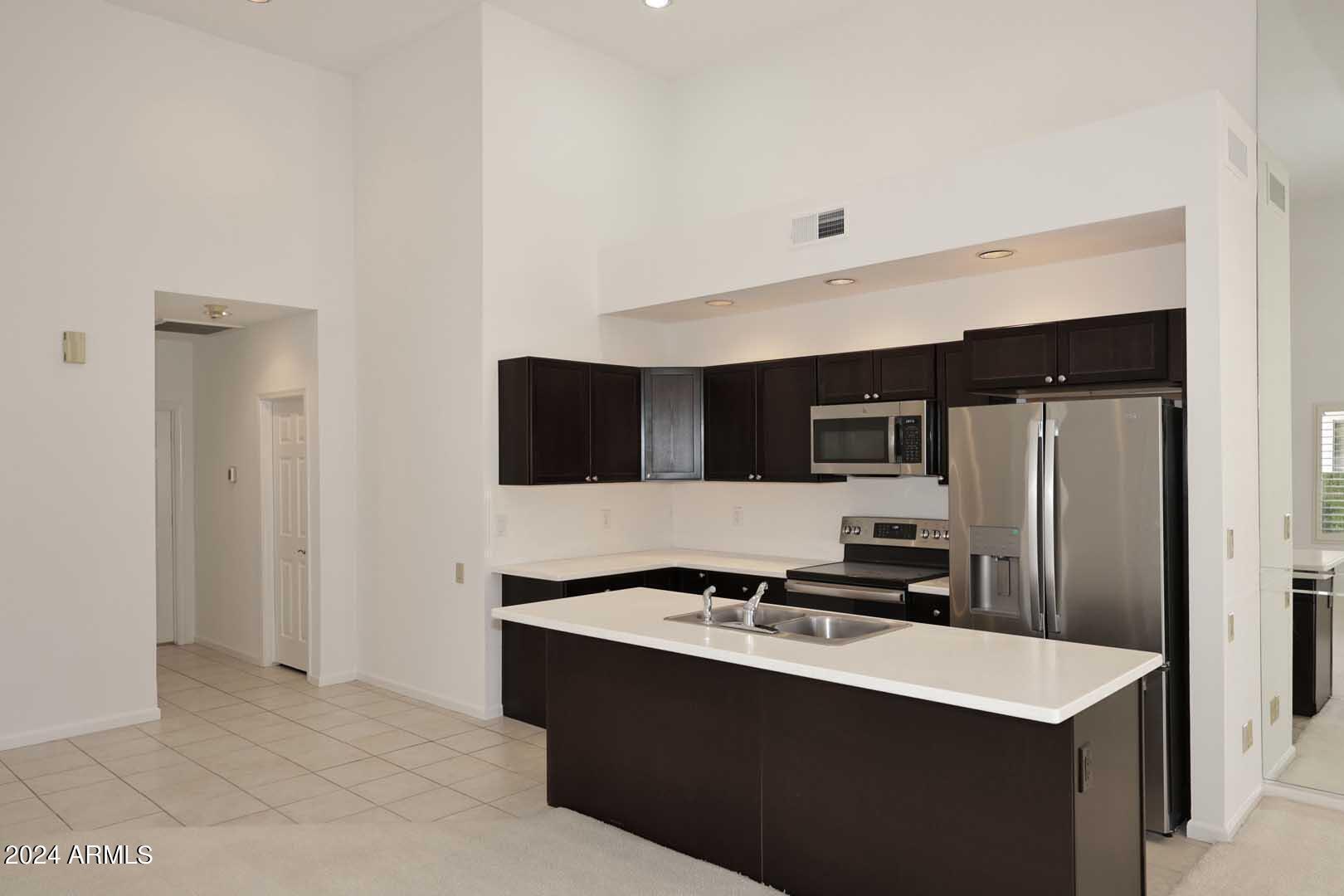 7272 East Gainey Ranch Road, Unit 55 Scottsdale, AZ 85258 - Photo 15 of 35 a kitchen with kitchen island stainless steel appliances a sink stove and refrigerator