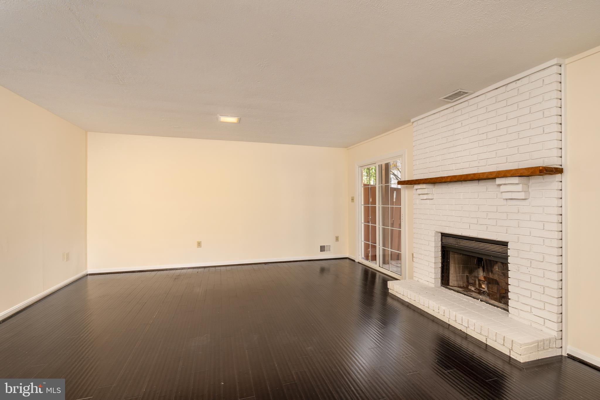 8010 Merry Oaks Lane Vienna, VA 22182 - Photo 26 of 33 an empty room with wooden floor and fireplace