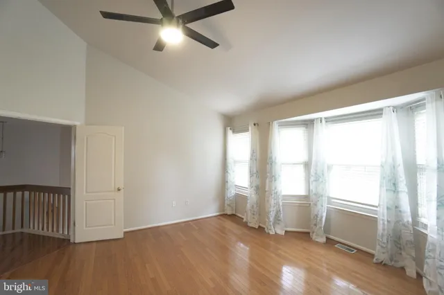 a view of an empty room with a window and wooden floor