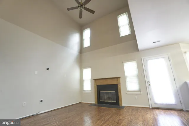 an empty room with windows fireplace and wooden floor