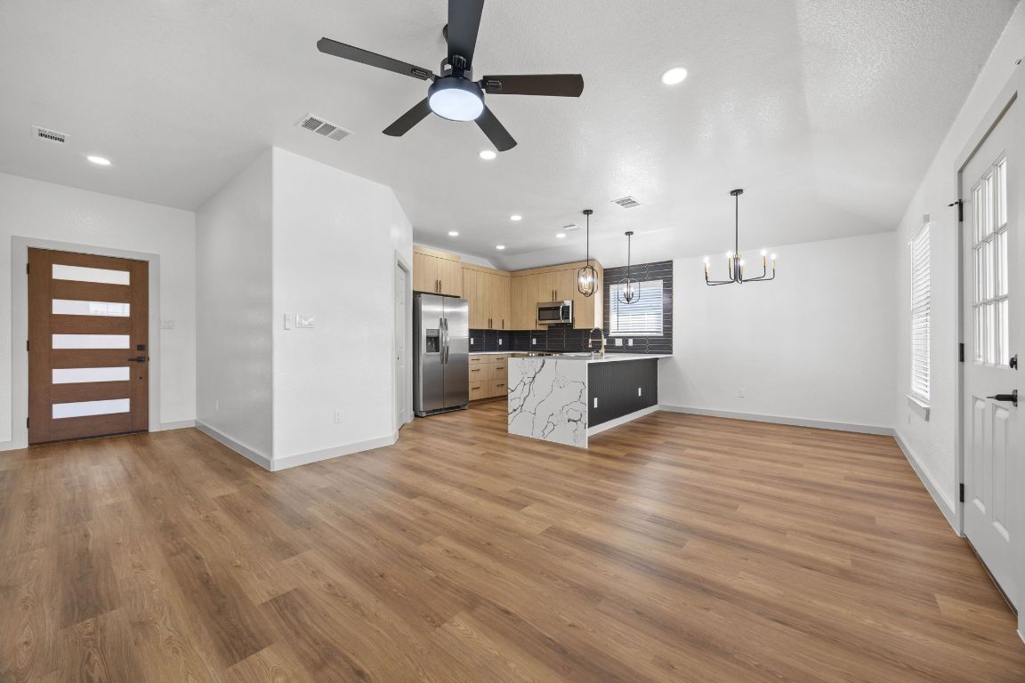2303 Thomas Street Taylor, TX 76574 - Photo 4 of 16 an empty room with wooden floor kitchen view and a ceiling fan