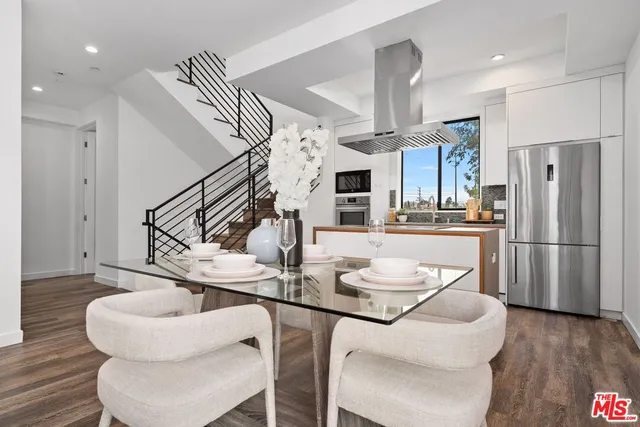 a kitchen with stainless steel appliances kitchen island granite countertop a table chairs and a refrigerator