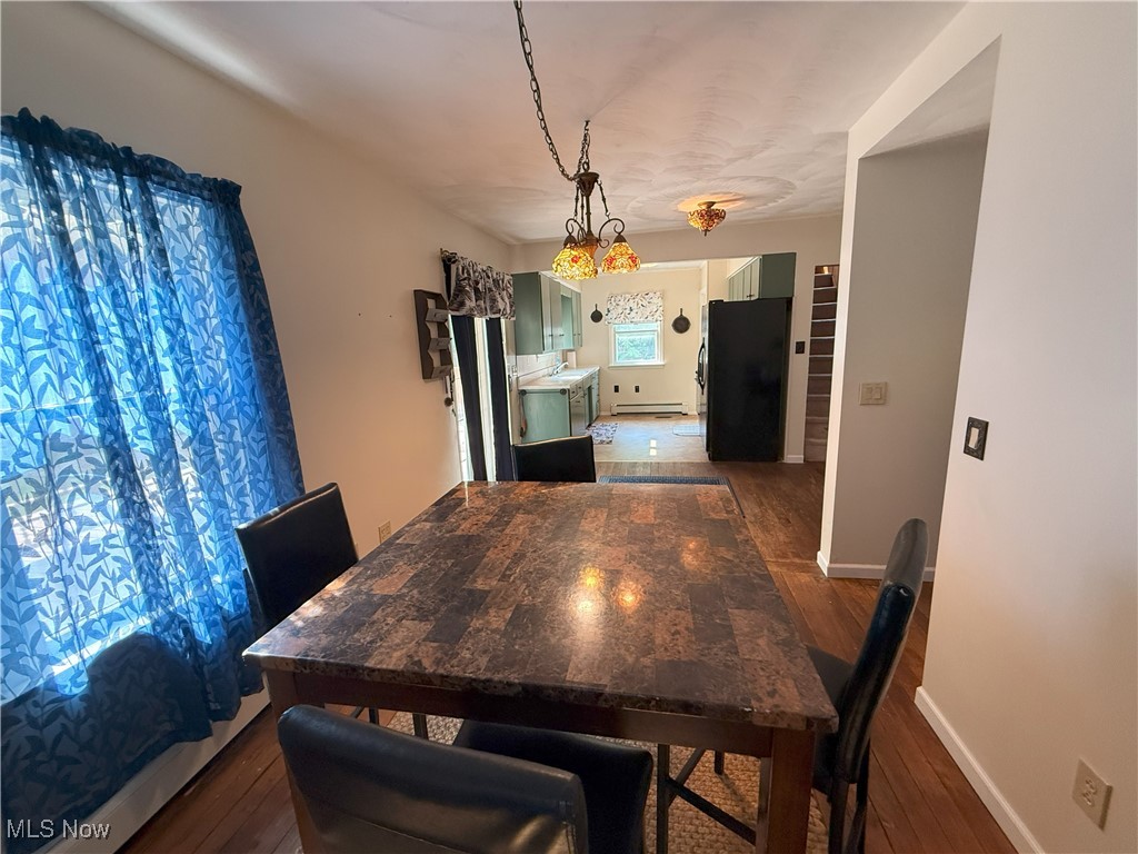 Dining space featuring baseboard heating and dark wood-style flooring