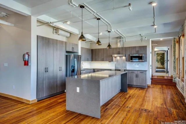 a large kitchen with stainless steel appliances granite countertop a lot of cabinets and wooden floor