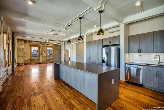 a large kitchen with stainless steel appliances granite countertop a lot of counter space and wooden floors