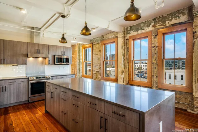 a large kitchen with stainless steel appliances granite countertop a stove and a wooden floors