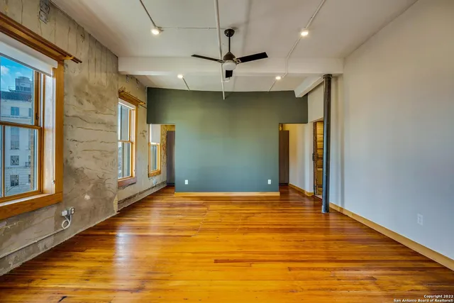 a view of an empty room with window and a kitchen