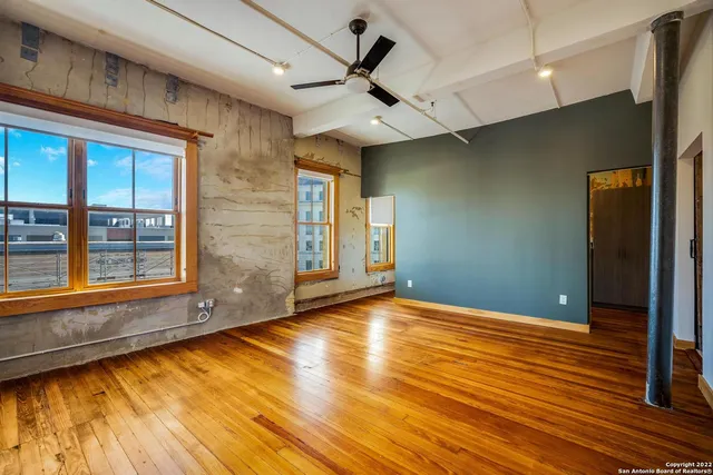 a view of an empty room with window and wooden floor