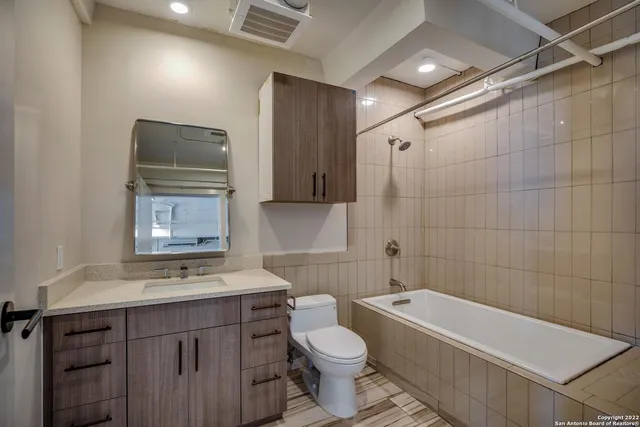 a bathroom with a bathtub shower sink mirror vanity and toilet
