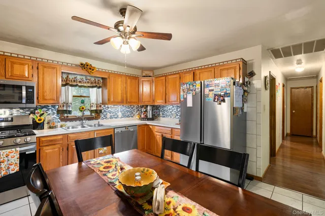 a kitchen with stainless steel appliances granite countertop a refrigerator a stove a sink dishwasher a dining table and chairs with wooden floor