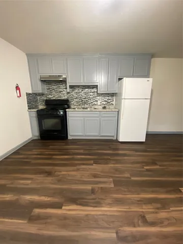 a kitchen with granite countertop a refrigerator stove and white cabinets