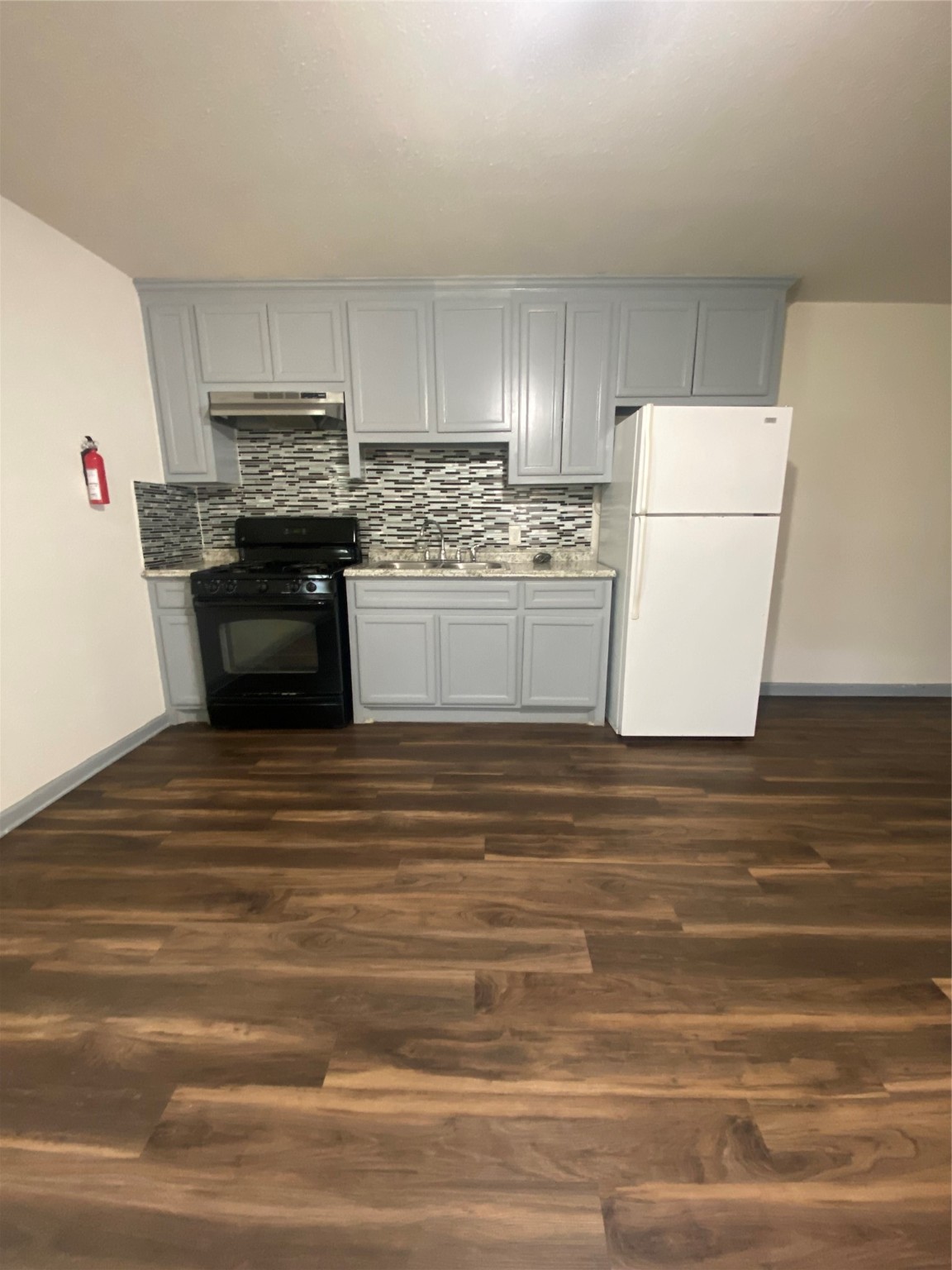 5301 Collingsworth Street, Unit 8 Houston, TX 77026 - Photo 5 of 8 a kitchen with granite countertop a refrigerator stove and white cabinets