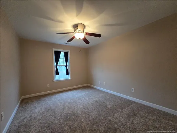 an empty room with a window and a fan