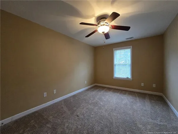 an empty room with windows and fan