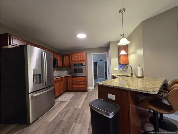 a kitchen with stainless steel appliances granite countertop a refrigerator a sink dishwasher a stove and a refrigerator