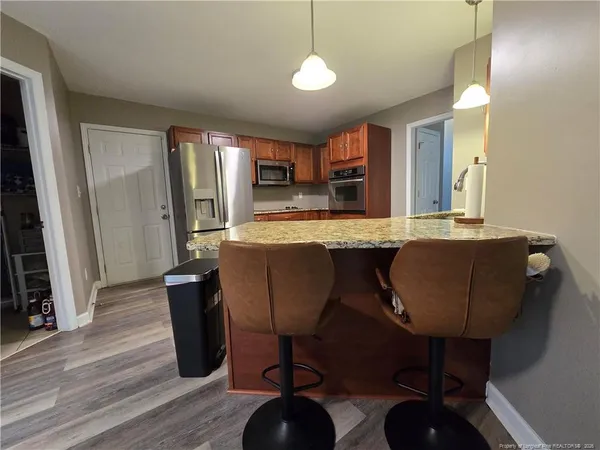 a living room with stainless steel appliances kitchen island granite countertop furniture and a flat screen tv