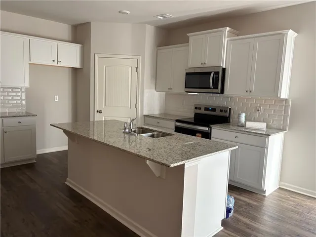 a kitchen with stainless steel appliances granite countertop a sink a stove and a refrigerator