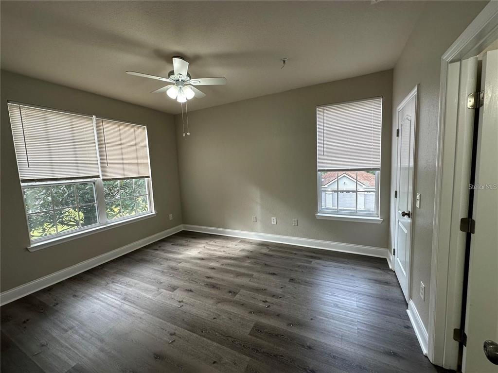 3307 South Kirkman Road, Unit 129 Orlando, FL 32811 - Photo 19 of 24 an empty room with wooden floor chandelier fan and windows