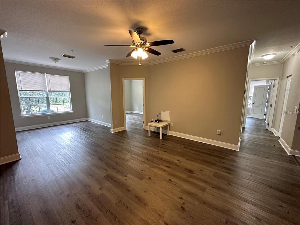 3307 South Kirkman Road, Unit 129 Orlando, FL 32811 - Photo 4 of 24 a view of an empty room with wooden floor and a window