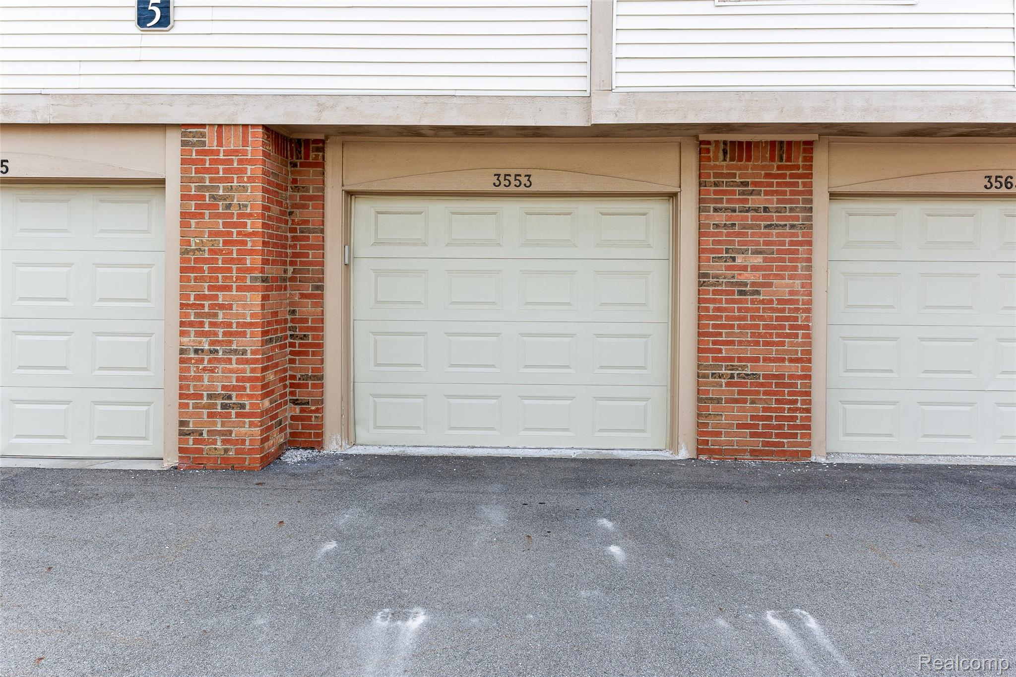 3553 Oakmonte Boulevard Rochester, MI 48306 - Photo 30 of 42 Individual garage access featuring panel doors, brick accents, and asphalt paving