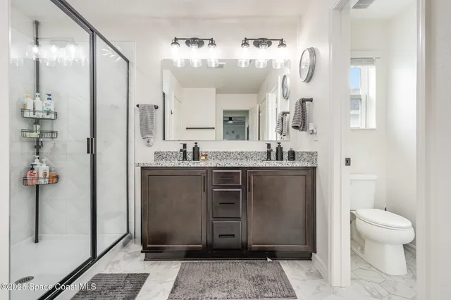 a bathroom with a granite countertop sink a toilet a mirror and shower