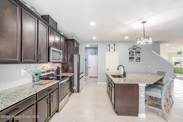 a kitchen with stainless steel appliances granite countertop a sink a oven a dining table and chairs with wooden floor