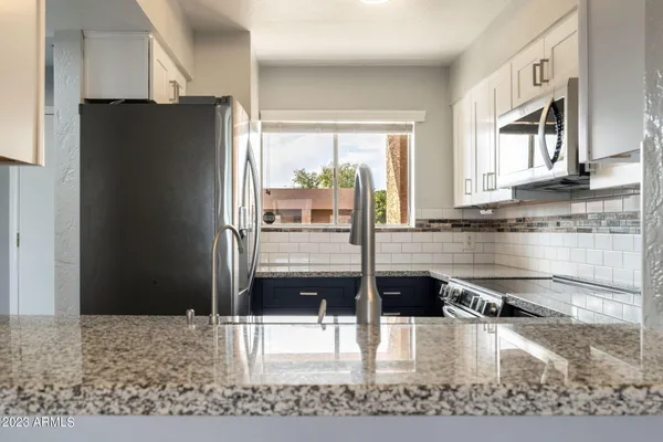 a kitchen with granite countertop a refrigerator and a sink