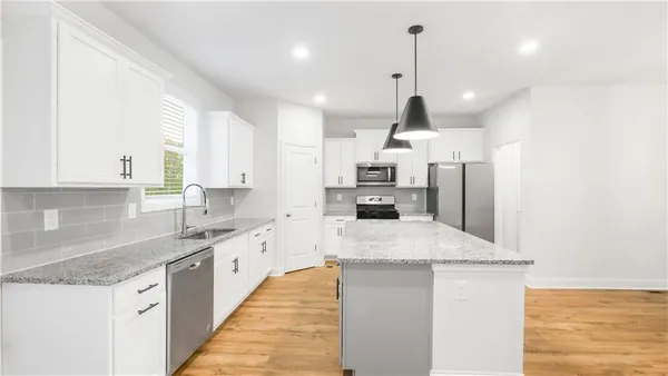 a large kitchen with stainless steel appliances kitchen island granite countertop a sink a stove and refrigerator