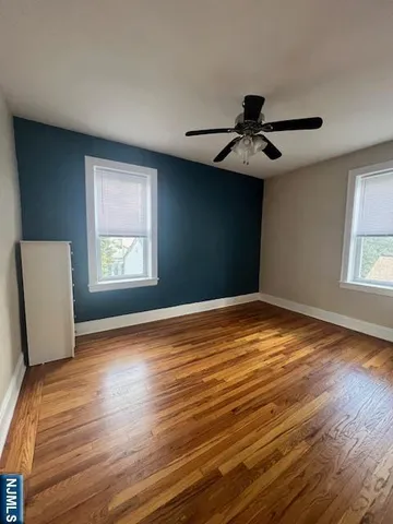 a view of empty room with wooden floor and fan