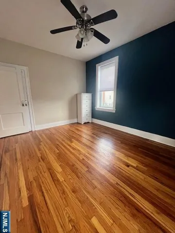a view of an empty room with window and wooden floor