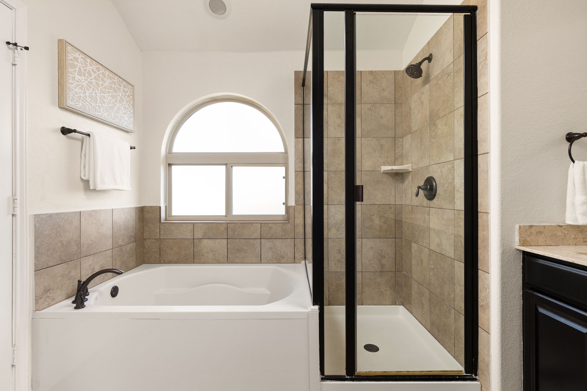 2400 Leonards Pass Leander, TX 78641 - Photo 30 of 40 An arched window bathes this tranquil bathroom in natural light, complementing the soaking tub and enclosed shower.