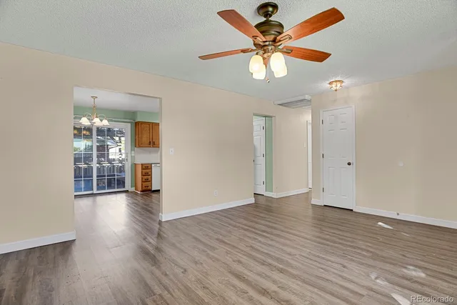 a view of an empty room with window and wooden floor