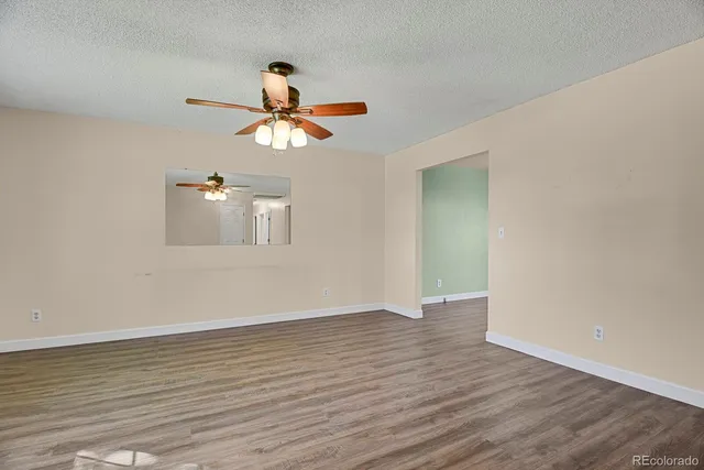 a view of a room with wooden floor and ceiling fan