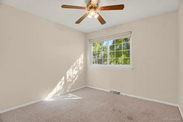an empty room with windows and fan