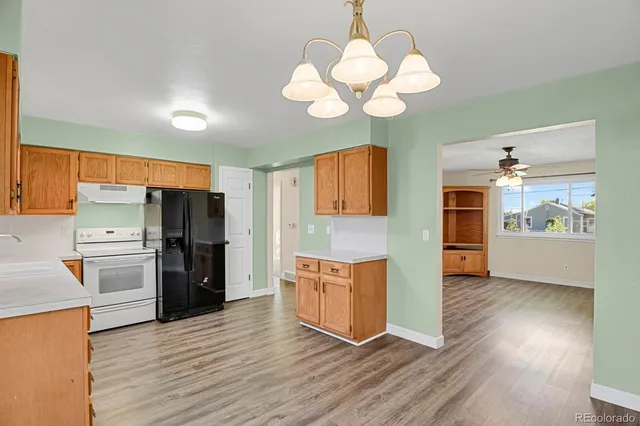 a kitchen with stainless steel appliances granite countertop a refrigerator a stove and a wooden floors