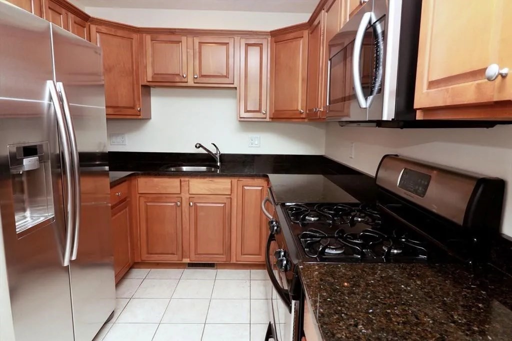 132 Howe Street, Unit B Natick, MA 01760 - Photo 15 of 32 a kitchen with stainless steel appliances granite countertop a stove a sink and a microwave