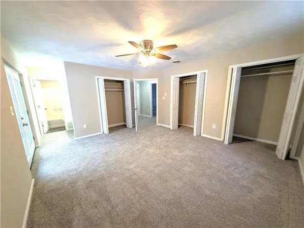 an empty room with closet and a chandelier fan