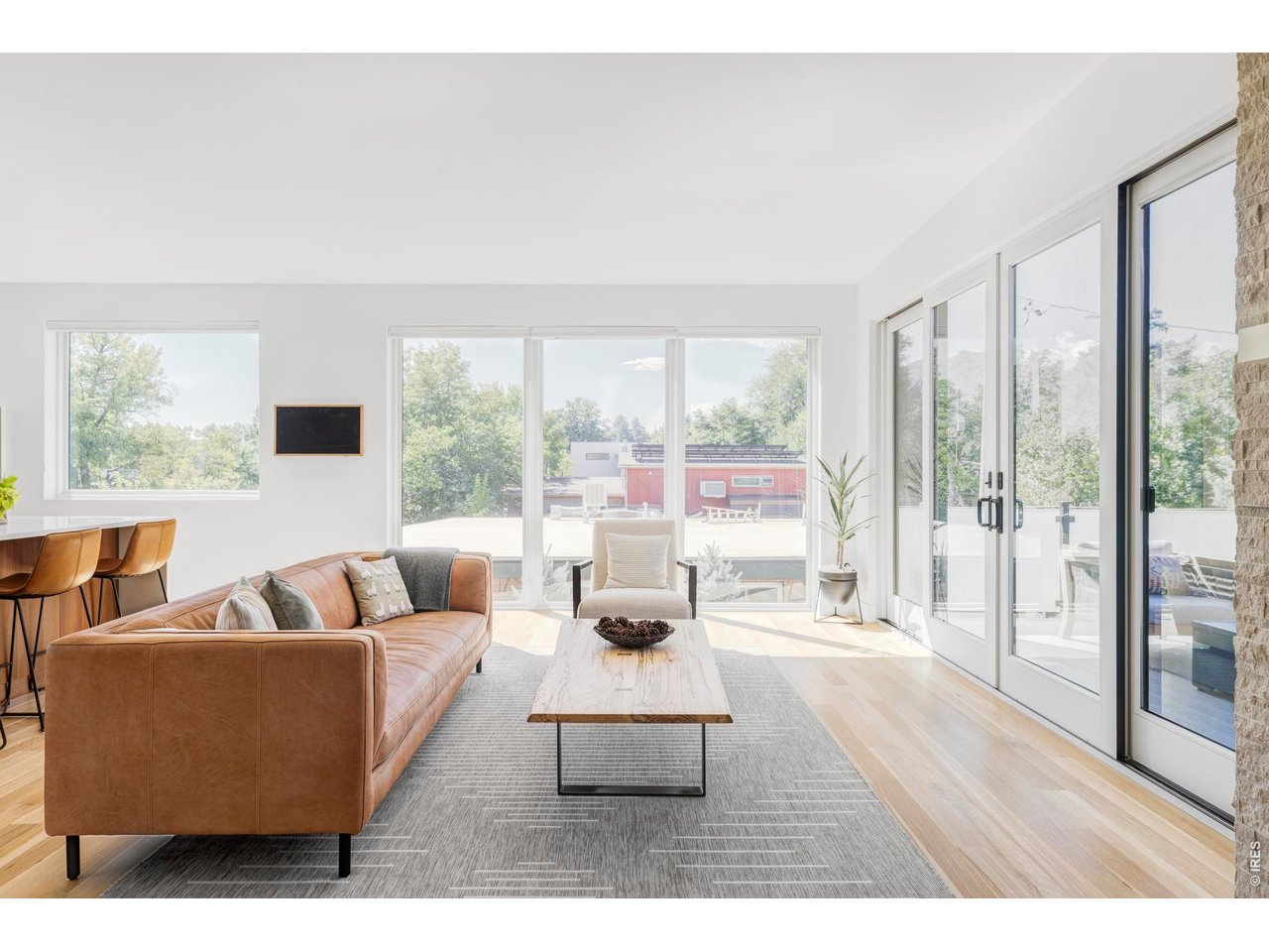 2895 18th Street Boulder, CO 80304 - Photo 11 of 29 The living room offers both warmth and sophistication with floor-to-ceiling windows, a stone fireplace, and double glass doors opening to the deck.
