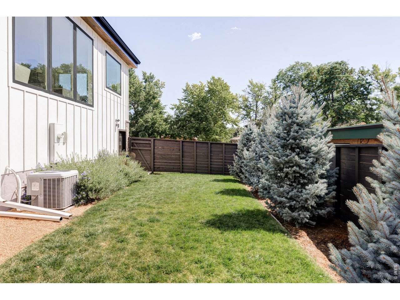 2895 18th Street Boulder, CO 80304 - Photo 25 of 29 Outdoors, the fenced yard wraps around the home with distinct areas, including garden plots, grassy lawns, and trees for added privacy.